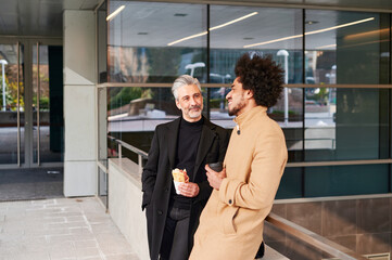 Smiling businessmen talking outside during a lunch break