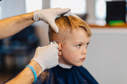 Shy Young Boy Getting clipper Haircut at Barber Shop