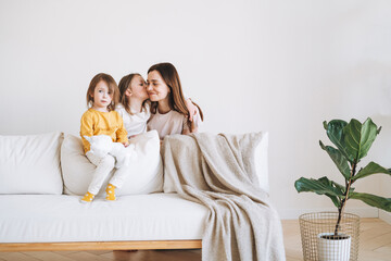 Young happy family with one parent woman mother with two children girls on couch in living room...