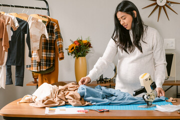 Pregnant dressmaker looking at fabrics on worktable