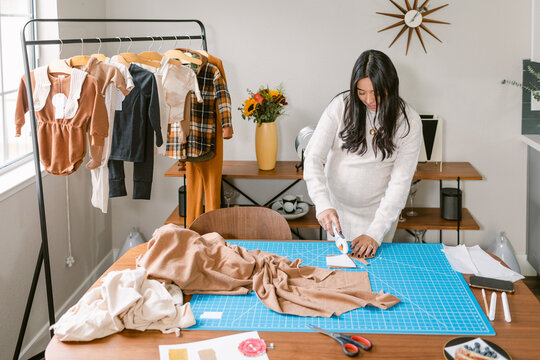 Pregnant dressmaker entrepreneur cutting fabric