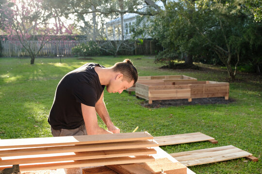 Man Building Raised Garden Beds In His Backyard At Home