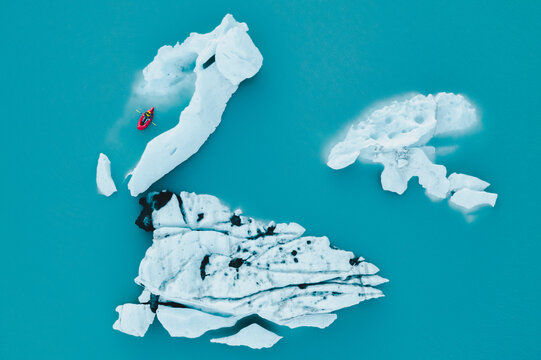 Man Packrafts Around Glacier Ice in Red Raft in Alaska