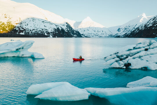 Man Packrafts Around Glacier Ice in Red Raft in Alaska
