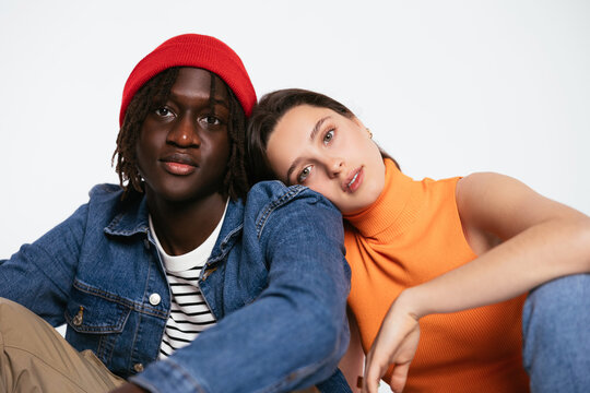 Trendy diverse couple cuddling and sitting in studio