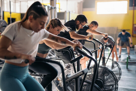 Motivated people exercising on cycling machine in gym
