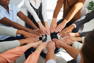 Team of happy diverse people holding hands in a circle. Different young multi ethnic multicultural males and females putting hands together. Teamwork, community, help, support, group therapy concept