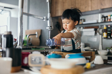 Asian little baby boy wash bottle by himself