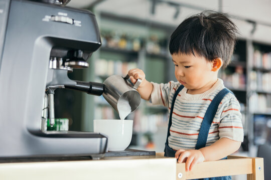 Asian little baby boy making coffee with the coffee machine
