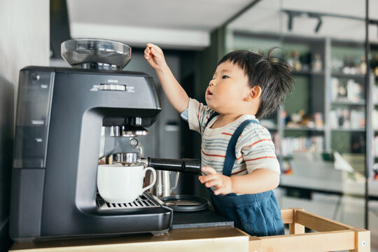 Asian little baby boy making coffee with the coffee machine