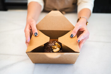Baker putting chocolate cake into delivery box