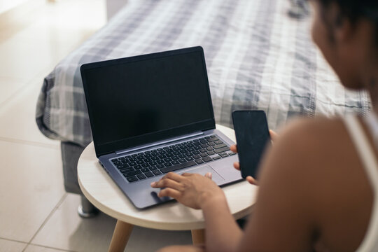 Anonymous woman with laptop and cellphone at home