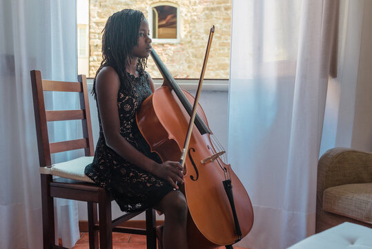 Girl with cello by an open window