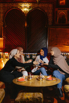 Group of diverse muslim friends sitting at tea house table
