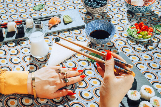 Stylish female eating with chopsticks japanese food.