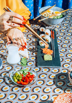 Stylish female eating with chopsticks japanese sushi.