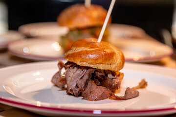 Mini burger with beef, pickled cucumber and onion is on a plate