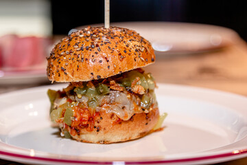 Mini burger with beef, pickled cucumber and onion is on a plate