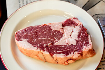 A rib-eye cut of good marbled beef lies in the restaurant, waiting to be cooked