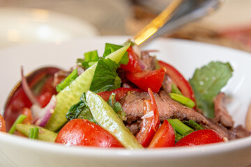 Vegetable salad of tomatoes, cucumbers and onions with fried beef