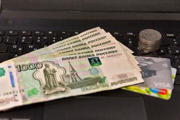 Russian paper money bank cards and a stack of coins on a computer keyboard