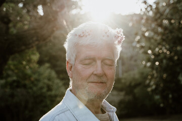 Portrait of happy senior man with closed eyes with flowers