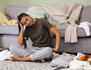 When does the laundry end. Shot of a young woman looking tired while cleaning at home.