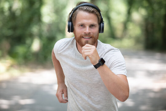athletic man is running wearing smartwatch and headphones