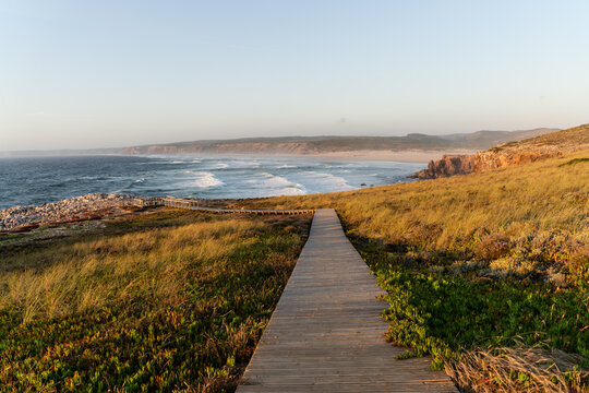 Sunset beach landscape with wooden path to the sea