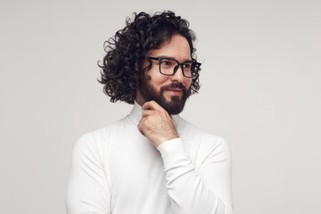Fototapeta na wymiar Smart male in glasses touching chin in studio