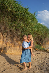 little girl hugging her mom at sunset on the beach near the sea. family portrait
