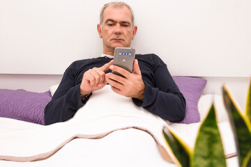 man chatting or sending message with phone in bed