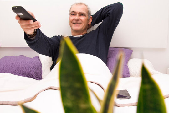 Relaxed Man In Bed With Tv Remote Looking For A Program