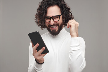 Cheerful man reading exciting message on smartphone