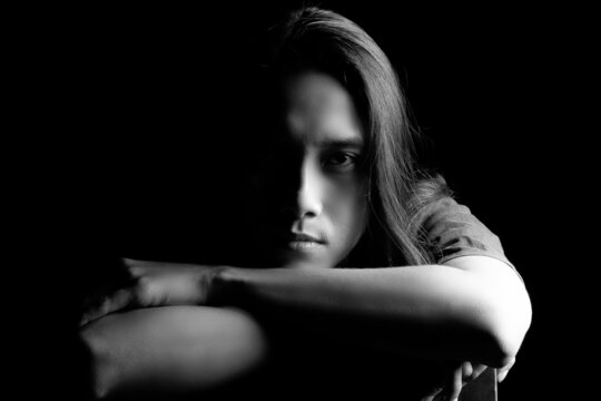 headshot of asian long hair man portrait in darkness
