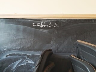 Poorly washed blackboard, with the date of the start of the war, February 24 in Hungarian. Room for refugees in a Hungarian school. Shpolny class equipped for immigrants.