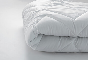 Folded soft white blanket, quilt or bedspread on a white background.