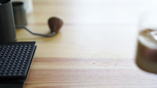 hand of barista grab small cup of chilled latte coffee on wood table