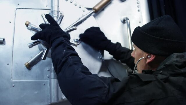 Close up of a bank robber cracking a safe. The safecracker uses a stethoscope to crack the vault security lock