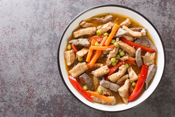 Igado is a popular dish from the Philippines made from pork tenderloin, pork liver, and vegetables closeup in the plate on the table. Horizontal top view from above