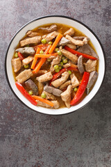 Igado is a Filipino spiced pork and liver dish closeup in the plate on the table. Vertical top view from above