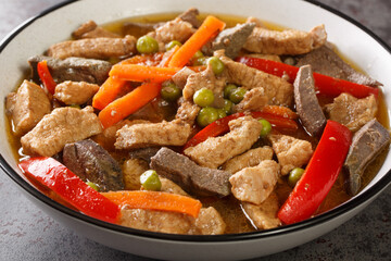 Pork Igado is an Ilocano stew made of strips of liver and pork tenderloin braised in a tangy and savory soy sauce closeup in the plate on the table. Horizontal