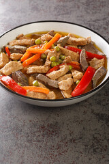 Filipino food Igado is a popular Ilocano dish made from pork tenderloin and innards with vegetables closeup in the plate on the table. Vertical