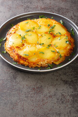 Pan haggerty is a traditional Northumbrian vegetarian side dish containing potatoes, onion and cheese closeup in the plate on the table. Vertical