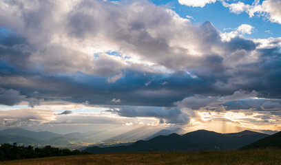 Sunset dramatic sky over Fabriano city, Marche, Italy. Sunbeams among clouds above unique hills and mountains landscape, emotional feeling concept.