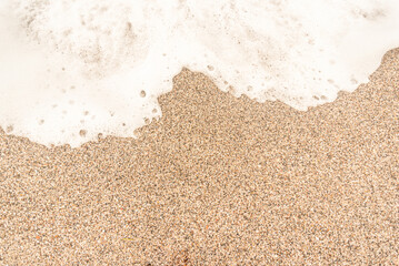 Fototapeta na wymiar Coarse sand on beach with sea foam