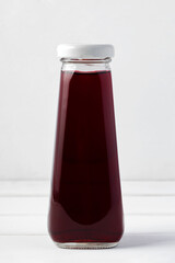 Small glass bottle of fresh juice on white background