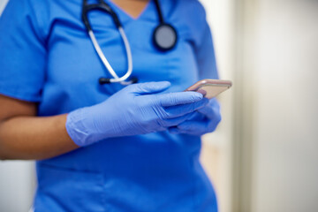 Checking her texts before heading in to perform another surgery. Shot of an unrecognisable surgeon using a cellphone in a hospital.