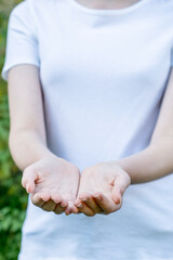 Girl wearing mockup white t-shirt with hands outstretched showing empty palms. Giving held out. Template copy space