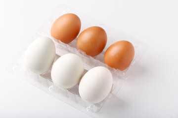 3 Duck eggs (White color) and 3 chicken eggs (Brown color) arranged in plastic packaging boxes for sale.